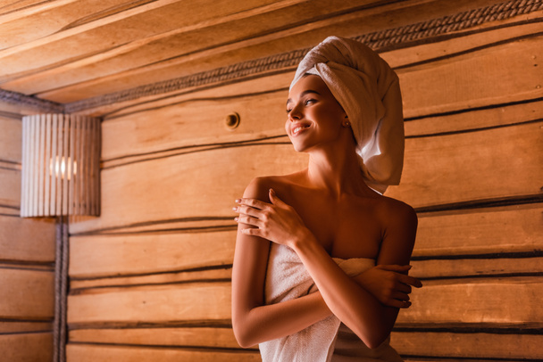 Mujer feliz relajante en sauna de madera sobre fondo borroso  - Foto, Imagen