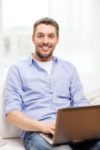 Smiling man working with laptop at home - 写真・画像