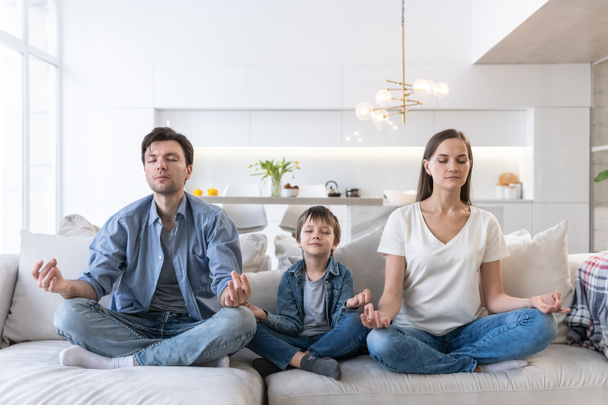 Family sits on the sofa and meditates - Photo, Image