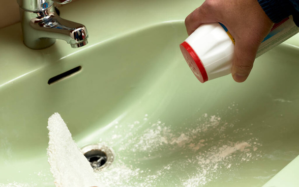 Az ember fertőtlenítőporral mossa a mosogatót.  - Fotó, kép