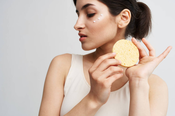 Beautiful brunette holding a sponge in her hands clean health skin close-up - Photo, Image