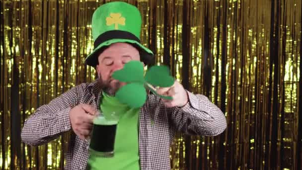 Beyaz sakallı adam elinde bir bardak yeşil bira tutuyor ve yonca kokuyu soluyor ve tadını çıkarıyor. Aziz Patrick Günü Kutlama Konsepti. - Video, Çekim