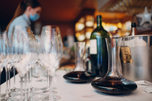 официант наливает элитное красное вино в графин на стол в ресторане - Фото, изображение