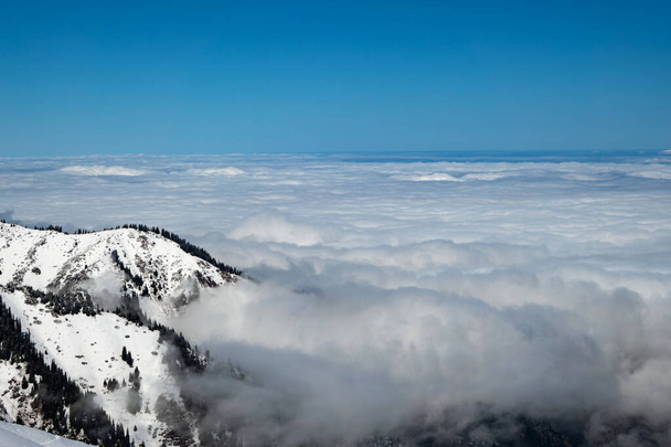 Горный зимний пейзаж. Выше облаков. В основном облачно. Алматинская область. Горы Тянь-Шаня. Казахстан - Фото, изображение