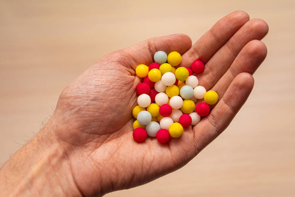 multicolored sugar tablets in the palm. Candy in the form of balls of different colors in hand - Photo, Image