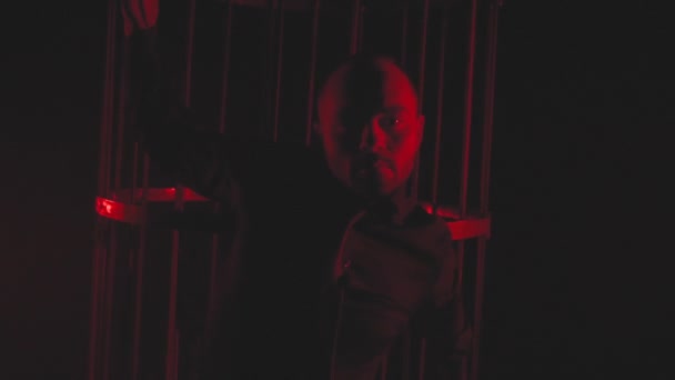 Чоловік в чорному в червоному світлі в димі біля металевої клітки
 - Кадри, відео