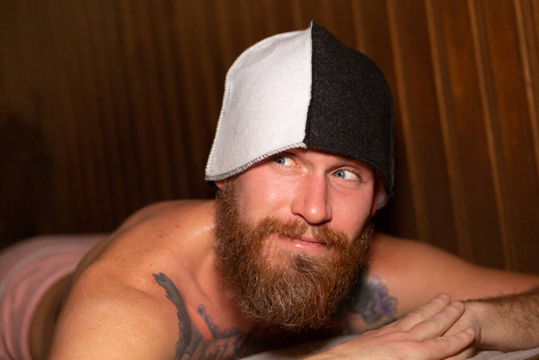Портрет жорстокого чоловіка з бородатою шапочкою на голові лежить у спа-саун, процес очищення здоров'я
 - Фото, зображення