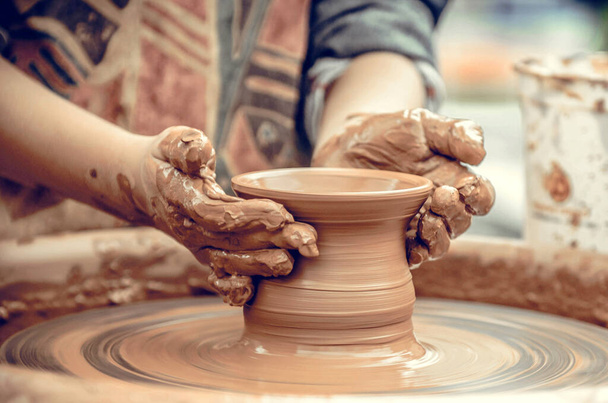 Handen van een pottenbakker aan het werk. Pottenbakker maakt keramische mok op het aardewerk wiel - Foto, afbeelding