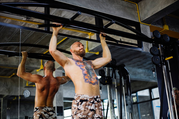 Arka Kollar Antrenman Sporcusu Güçlü kaslı spor dövmeli atletik adam kaslarını şişiriyor  - Fotoğraf, Görsel