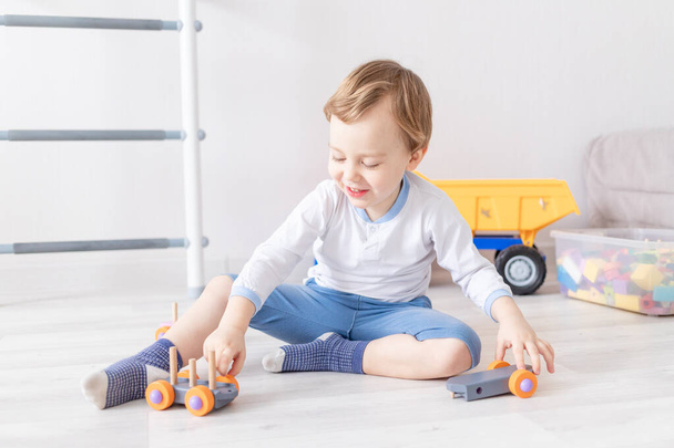 kisfiú játszik fából készült játékokat otthon a földön - Fotó, kép