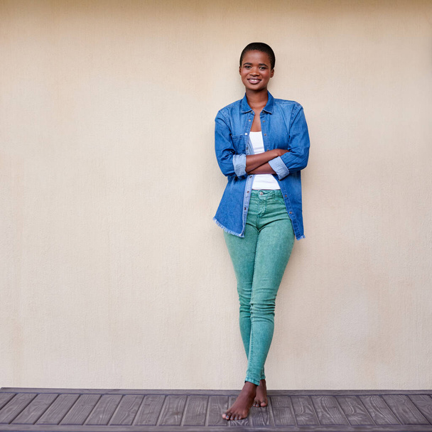 Портрет молодої афроамериканської жінки, яка посміхається, стоячи зі схрещеними руками на подвір "ї. - Фото, зображення
