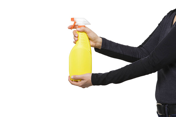 La donna tiene in mano una bottiglia di detergente spray nebbioso giallo acqua. Flacone spray giallo. - Foto, immagini