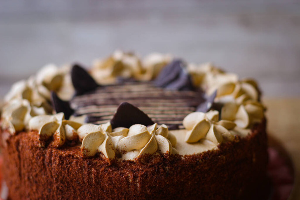 Pyszne ciasto czekoladowe pokryte kawałkami czekolady i zwieńczone dekoracją maślaną - Zdjęcie, obraz