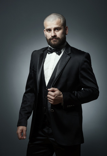 Stylish and brutal bald man with a beard in elegant black suit - Photo, Image
