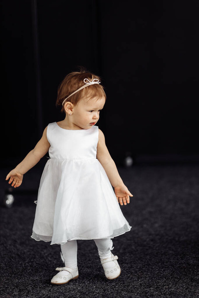little girl in a dress on a black background - Фото, изображение