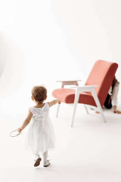 little girl in a white dress near chair - Zdjęcie, obraz
