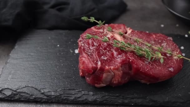 świeże mięso z surowego mięsa wołowego na czarnym kamiennym talerzu. mięso i przyprawy na stole kuchennym - Materiał filmowy, wideo