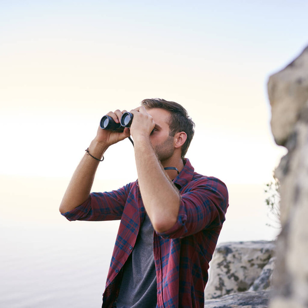 Mladý muž se pozorně dívá dalekohledem, zatímco venku na horské stezce si užívá pozorování ptáků - Fotografie, Obrázek