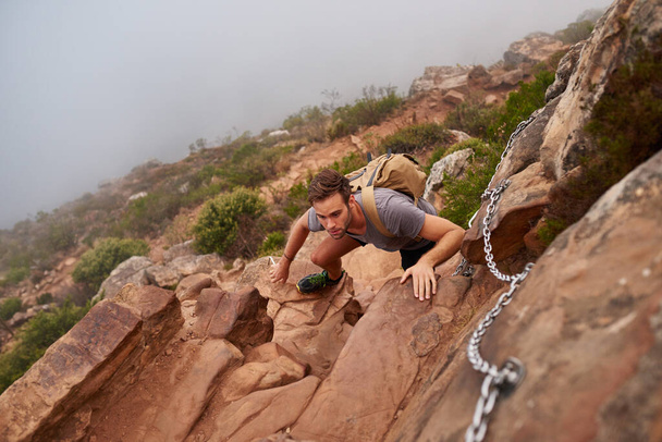 山の自然歩道に岩を登る若い男の高い角度のビュー - 写真・画像
