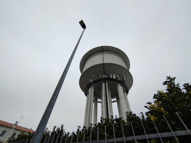 A water tower is an elevated building supporting a water tank constructed at a height sufficient to pressurize a water distribution system for the distribution of potable water, and to provide emergency storage for fire protection - Photo, Image