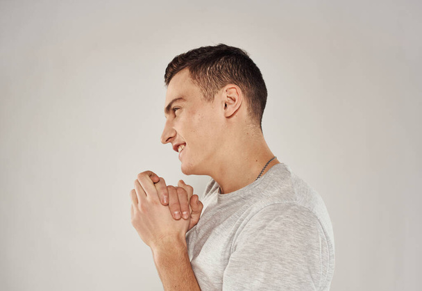 hombre alegre gesto con las manos en una camiseta blanca fondo claro recortado vista - Foto, Imagen
