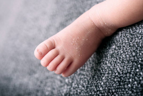 Battaniyeye karşı minik bebek ayağı, sığ bir tarla derinliği - Fotoğraf, Görsel