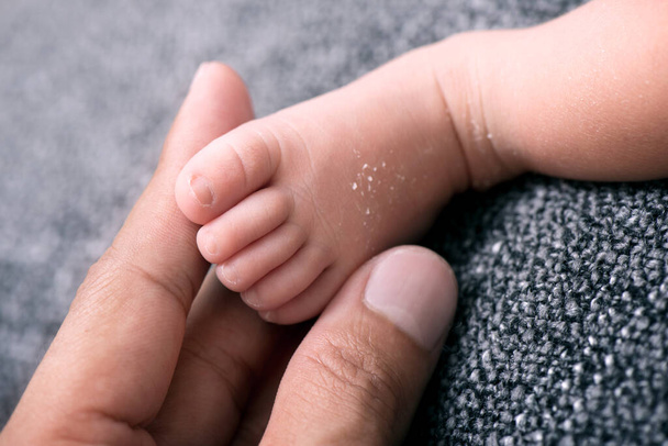 close-up kleine voet van pasgeboren baby tegen deken, ondiepe scherptediepte - Foto, afbeelding