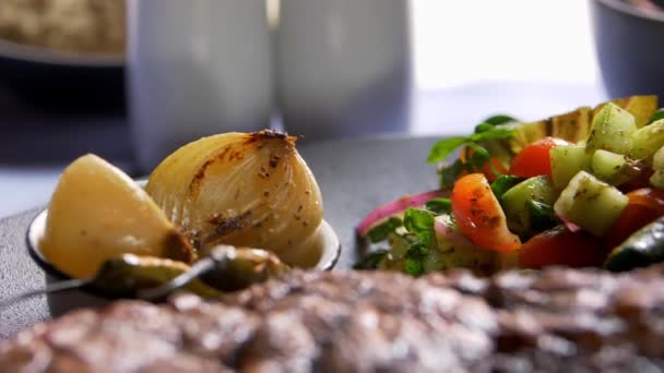 Mięso z grilla, sałatka, pieczona cebula i papryka chili na talerzu - Materiał filmowy, wideo