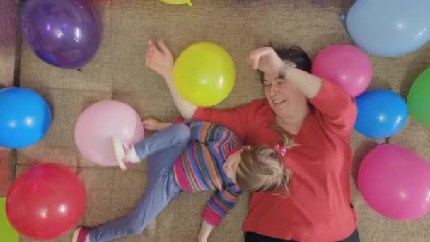 Grand-mère joue avec sa petite-fille dans des boules gonflables. Dessus de tir - Séquence, vidéo