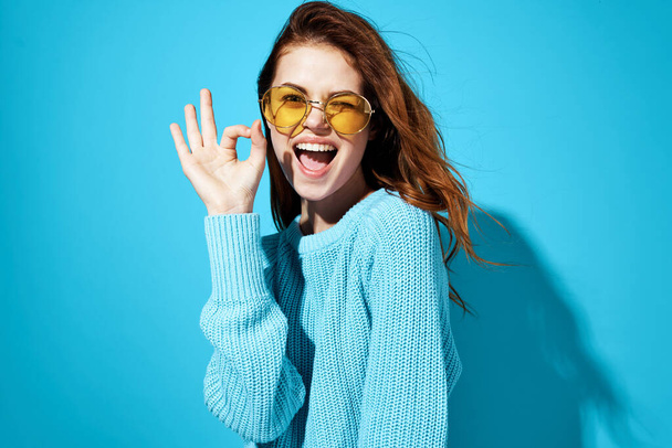 emotional woman with glasses and blue sweater lifestyle casual wear blue background - Photo, Image