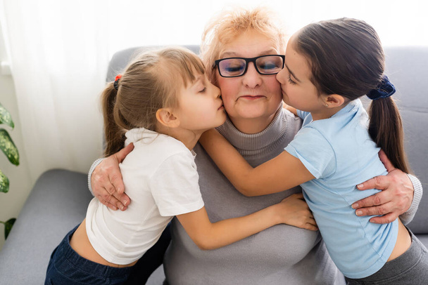 Счастливая взрослая бабушка средних лет и маленькая дошкольница две внучки развлекаются, играя дома - Фото, изображение