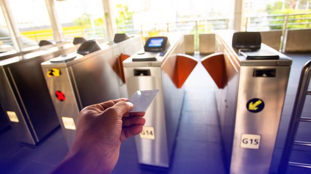 Selective focus to hand of passenger using smart card to open automatic gate machine at sky train station. Modern automatic ticket. Access control passenger of transportation concept. - Photo, Image