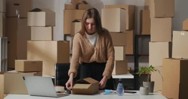 γυναίκα ξεπακετάρει κουτί με καλλυντικά στο σπίτι αποθήκη, μικρό εμπόριο ή προμηθεύτρια εταιρεία, κυρία των επιχειρήσεων ή διευθυντής - Πλάνα, βίντεο
