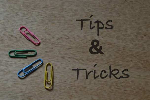 Vista superior de clips de papel sobre fondo de madera con texto TIPS y TRICKS. - Foto, Imagen