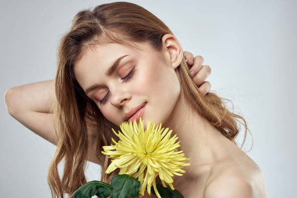 Portrét krásné ženy se žlutou květinou na světlém pozadí okouzlující úsměv model zrzavé vlasy - Fotografie, Obrázek