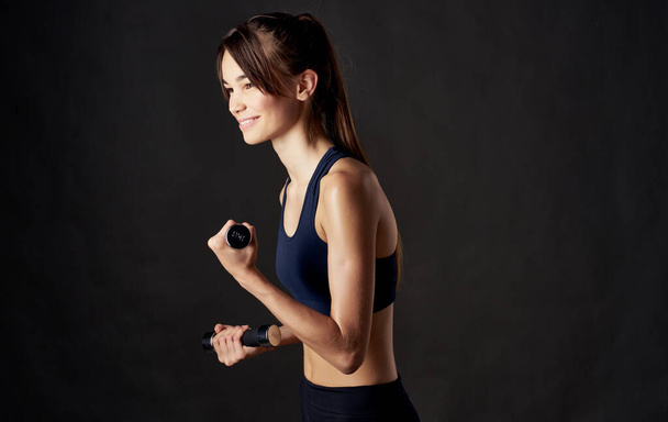 donna sportiva con manubri su uno sfondo scuro fitness figura sottile modello - Foto, immagini