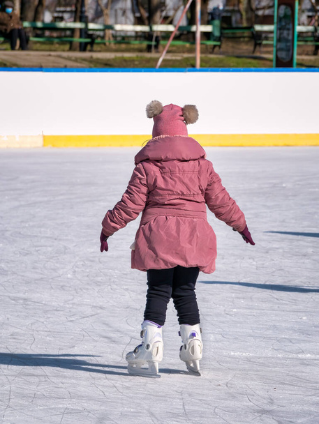 Vista trasera de una niña patinando sobre hielo en la pista de hielo del parque Cismigiu, en Bucarest - Foto, imagen