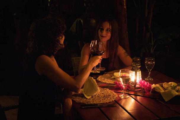 Twee brunettes klinkende glazen aan tafel - Foto, afbeelding