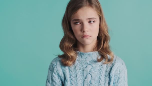 Menina adolescente loira perturbada sentindo-se triste por causa de más notas na escola posando na câmera sobre fundo azul. Rapariga ofendida - Filmagem, Vídeo