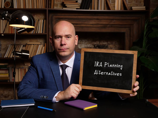 Hombre vistiendo traje de negocios azul y mostrando pizarra con texto escrito IRA Planning Alternatives . - Foto, Imagen