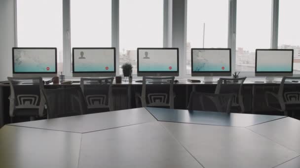 Inclinare ampio colpo di call center vuoto o ufficio help desk. Monitor di computer con interfaccia di software di servizio di cliente che sta su scrivanie da finestre panoramiche - Filmati, video