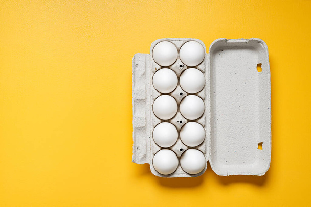 黄色の背景に開いた卵のカートンの白い鶏の卵。新鮮な鶏の卵の背景。コピースペース付きのトップビュー。箱の中の卵 - 写真・画像