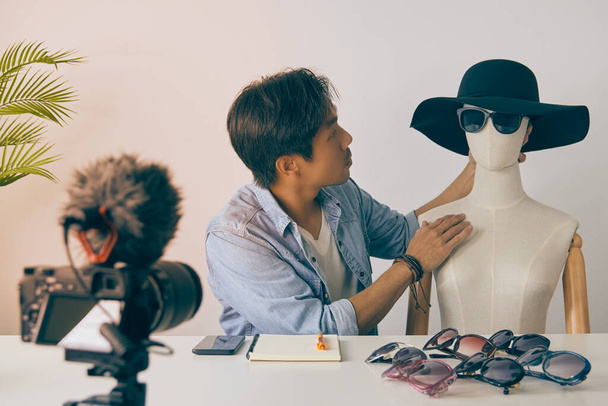 Asian Vlogger or Blogger Put Fashion Glasses to The Face of Mannequins and Recording Video. Freelancer Online Live Streaming with Customer Via Social Media in Vintage Tone - Photo, Image