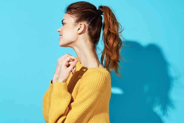 Frau in gelbem Pullover Mode Frisur Freizeitkleidung Studio ausgeschnitten Ansicht blauer Hintergrund - Foto, Bild