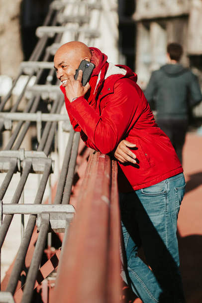 A young bald Latin male talking on his phone while walking in the city of Lyon - Fotografie, Obrázek