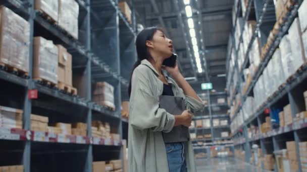 若いアジアのビジネス女性オンライン売り手は、小売ショッピングセンターに立ってデジタルタブレットを保持電話で顧客からの注文を確認話しています。物流、物流、出荷の準備ができてパッケージ. - 映像、動画