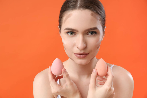 Krásná mladá žena s make-up houby na barevném pozadí - Fotografie, Obrázek