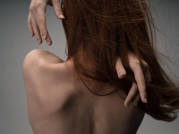 Achteraanzicht van sexy roodharige vrouw naakt rug aanraken met handen - Foto, afbeelding