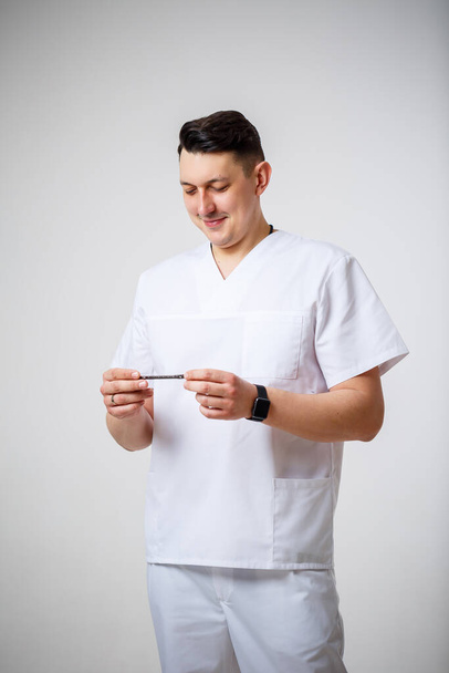 Fiatal férfi orvos fehér sebészeti ruha tartja, és vizsgálja titán lemezek csonttörés kezelésére.Izolált fehér alapon - Fotó, kép
