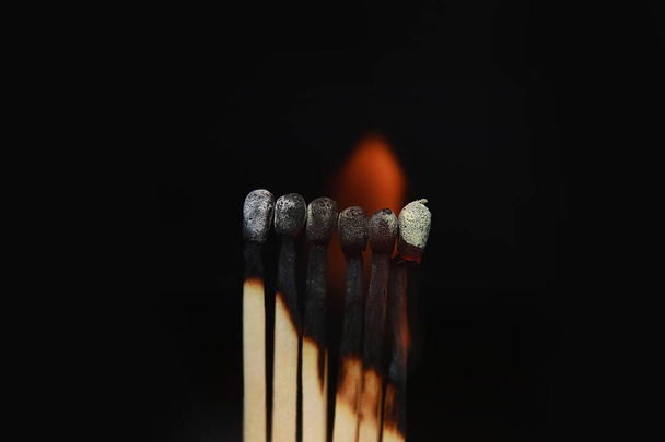 Burning matches on black background. matchsticks on fire in row of burning is sequence while one match stay down from burning to avoid fire connecting against black background. - Photo, Image